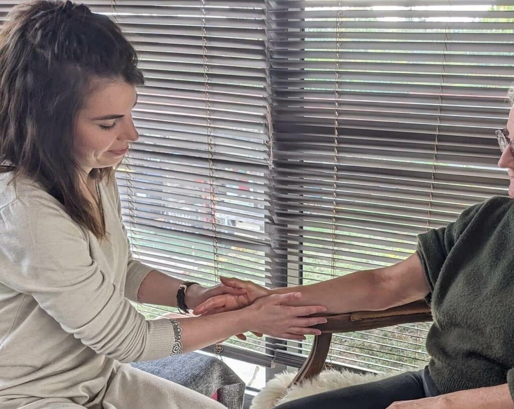 Justine Meu prodiguant un soin/massage de main à une femme - Mains Lumineuses